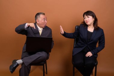 Yetişkin Japon iş adamı ve olgun Japon iş kadınının stüdyoda çekilmiş bir fotoğrafı.