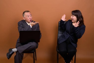 Yetişkin Japon iş adamı ve olgun Japon iş kadınının stüdyoda çekilmiş bir fotoğrafı.