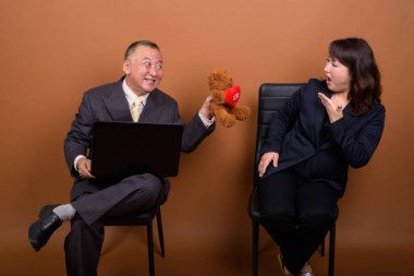 Yetişkin Japon iş adamı ve olgun Japon iş kadınının stüdyoda çekilmiş bir fotoğrafı.