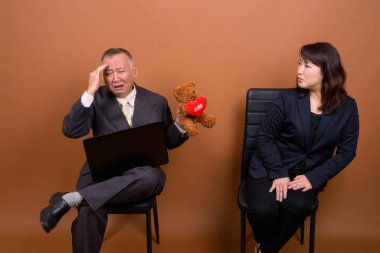 Yetişkin Japon iş adamı ve olgun Japon iş kadınının stüdyoda çekilmiş bir fotoğrafı.