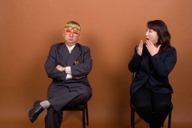 Yetişkin Japon iş adamı ve olgun Japon iş kadınının stüdyoda çekilmiş bir fotoğrafı.