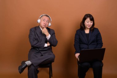 Yetişkin Japon iş adamı ve olgun Japon iş kadınının stüdyoda çekilmiş bir fotoğrafı.