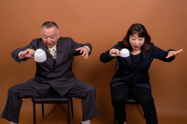 Yetişkin Japon iş adamı ve olgun Japon iş kadınının stüdyoda çekilmiş bir fotoğrafı.