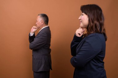 Yetişkin Japon iş adamı ve olgun Japon iş kadınının stüdyoda çekilmiş bir fotoğrafı.