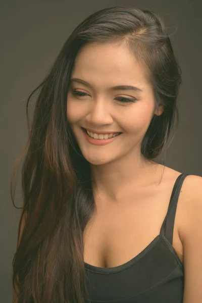 Gyönyörű fiatal ázsiai nő, sötétszürke háttérrel — Stock Fotó