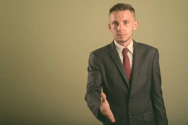 Joven hombre de negocios que usa traje contra fondo de color — Foto de Stock