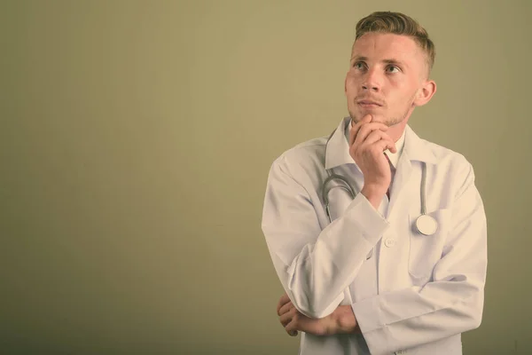 Portrét mladého muže lékaře na barevném pozadí — Stock fotografie