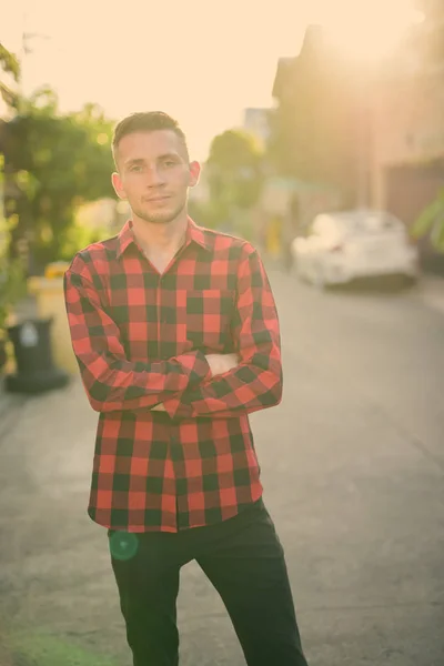 屋外の通りに赤いチェックのシャツを着た若い男 — ストック写真