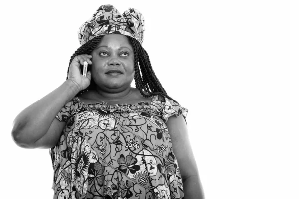 Nadváha africké ženy s tradičním oblečení myšlení při hovoru po telefonu — Stock fotografie