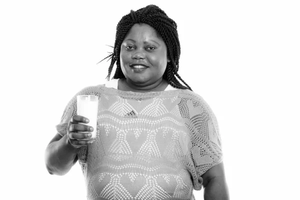 Studio záběr šťastné tlusté černošky africké ženy usmívá, zatímco drží sklenici mléka — Stock fotografie