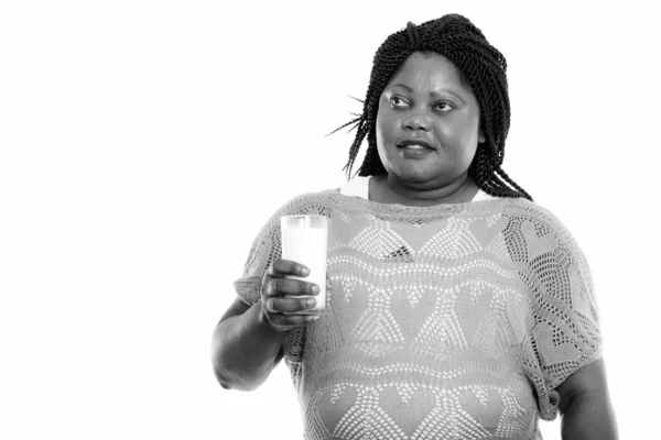 Studio záběr tlusté černošky africké ženy myšlení při držení sklenice mléka — Stock fotografie