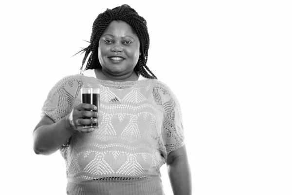 Studio záběr šťastné tlusté černošky africké ženy usmívá, zatímco drží sklenici limonády — Stock fotografie