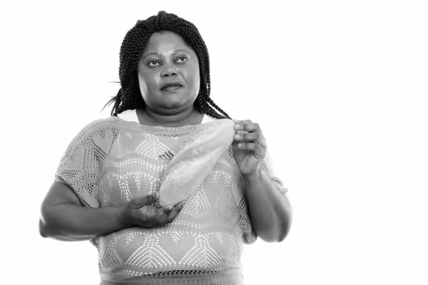 Studio záběr tlusté černošky africké ženy myšlení při držení chleba — Stock fotografie