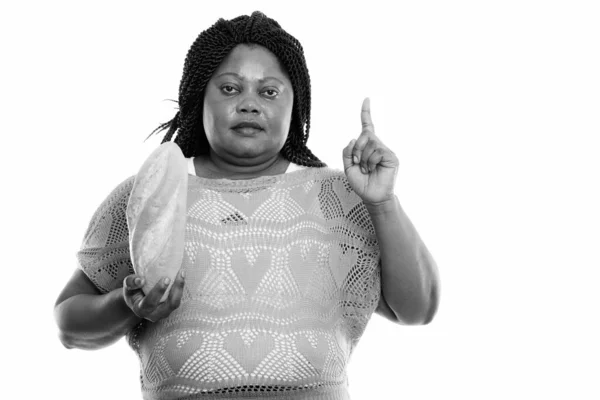 Studio záběr tlusté černošky africké ženy držící chléb a ukazující prstem nahoru — Stock fotografie
