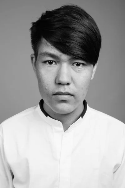 stock image Studio shot of young Asian teenage boy against gray background in black and white