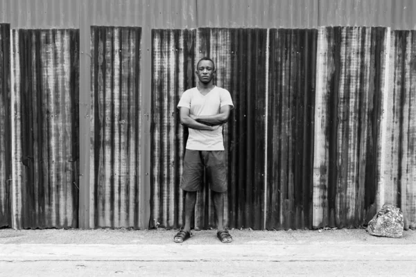 Νεαρός μαύρος Αφρικανός στέκεται με τα χέρια σταυρωμένα στον παλιό σκουριασμένο τοίχο — Φωτογραφία Αρχείου
