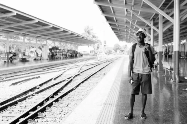Νεαρός ευτυχισμένος Αφρικανός τουρίστας περιμένει το τρένο στο σιδηροδρομικό σταθμό — Φωτογραφία Αρχείου