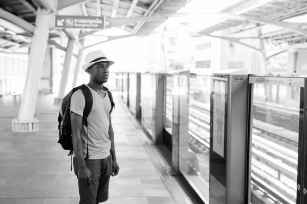 Junger afrikanischer Tourist steht am Bahnhof und denkt nach, während er auf den Zug wartet — Stockfoto