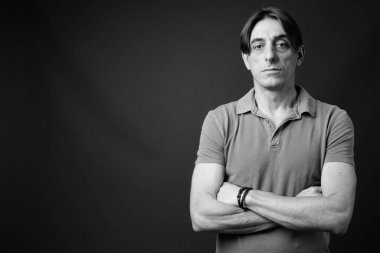 Siyah-beyaz gri arka planda olgun, yakışıklı bir İtalyan 'ın stüdyo fotoğrafı.