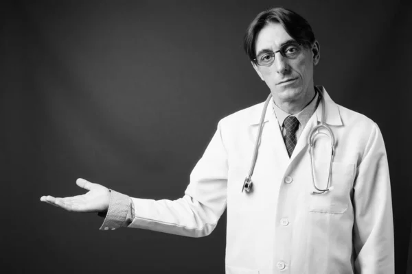 スタジオショットの成熟したハンサムなイタリア人医師に対してグレー背景で黒と白 — ストック写真