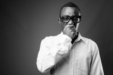 Studio shot of young African businessman against gray background in black and white