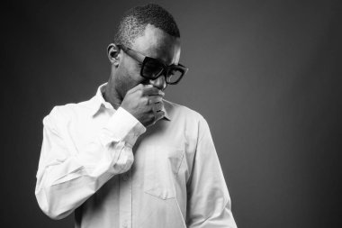 Studio shot of young African businessman against gray background in black and white