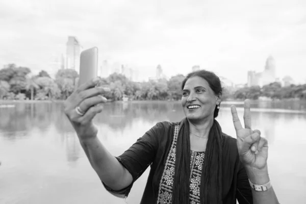 Mulher indiana madura feliz usando telefone no parque — Fotografia de Stock