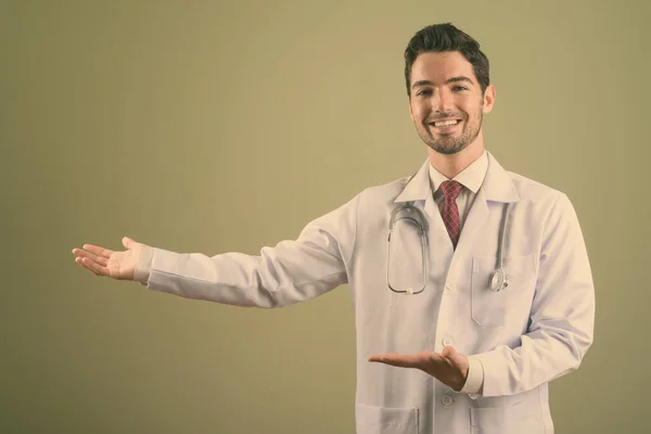Young handsome man doctor against colored background