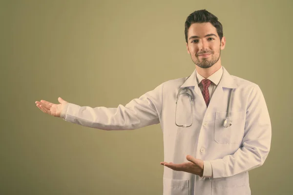 Junger schöner Mann Arzt vor farbigem Hintergrund — Stockfoto