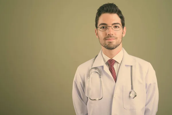 Junger schöner Mann Arzt vor farbigem Hintergrund — Stockfoto