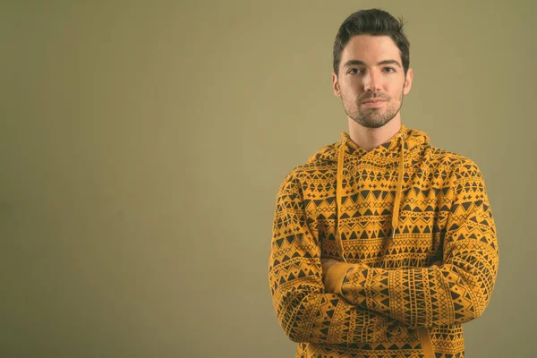 Junger gutaussehender Mann trägt Kapuzenpullover vor farbigem Hintergrund — Stockfoto