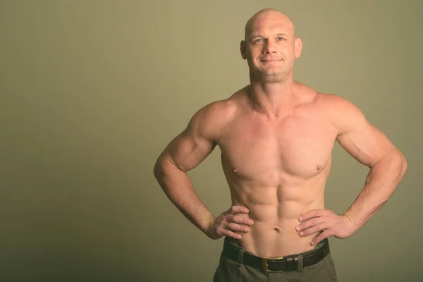Homem muscular careca sem camisa contra fundo colorido — Fotografia de Stock