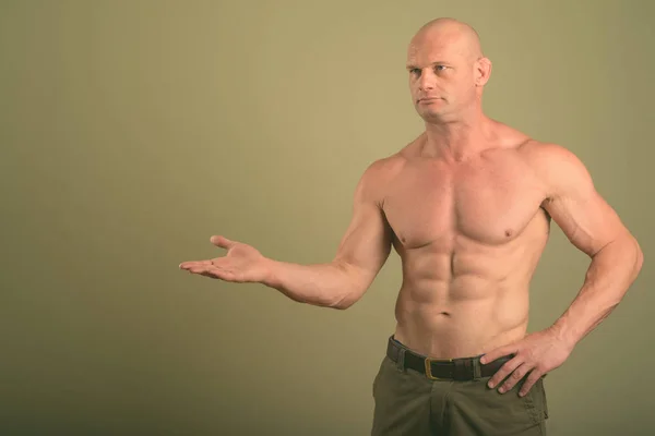 Glatzkopf, muskulöser Mann ohne Hemd vor farbigem Hintergrund — Stockfoto