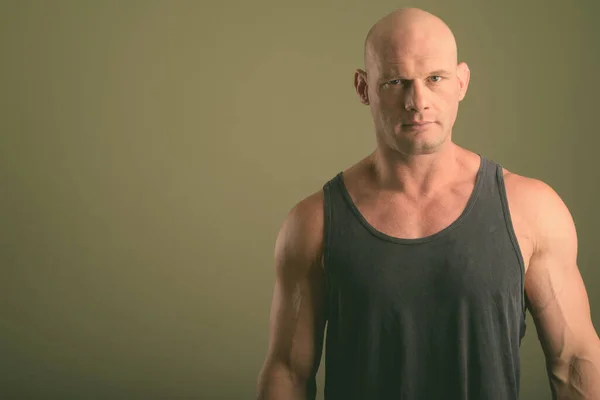 Calvo musculoso hombre usando camiseta sin mangas contra fondo de color —  Fotos de Stock