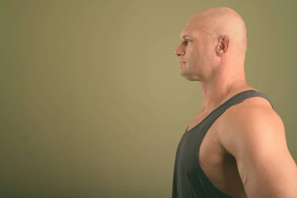 Calvo musculoso hombre usando camiseta sin mangas contra fondo de color —  Fotos de Stock