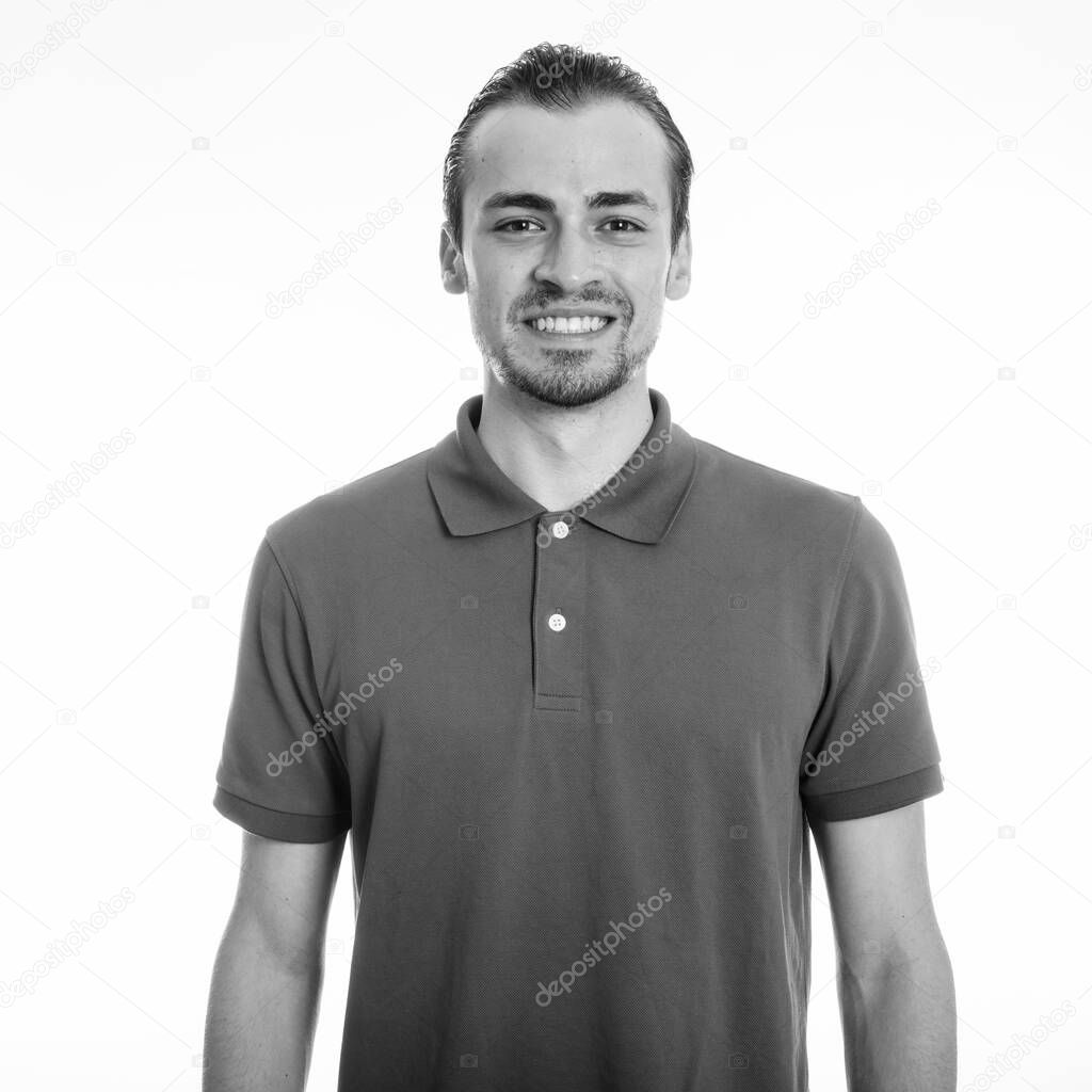 Studio shot of young handsome bearded man isolated against white background in black and white