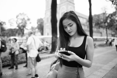 Portrait of young beautiful Asian tourist woman exploring Ho Chi Minh city in Vietnam in black and white