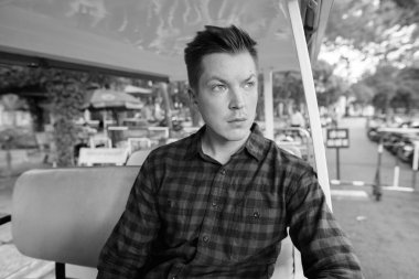 Portrait of young handsome tourist man exploring Ho Chi Minh city in Vietnam in black and white