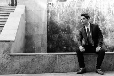 Portrait of young handsome businessman in suit exploring the city in black and white