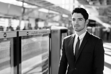 Portrait of young handsome businessman in suit exploring the city in black and white