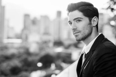Portrait of young handsome businessman in suit exploring the city in black and white