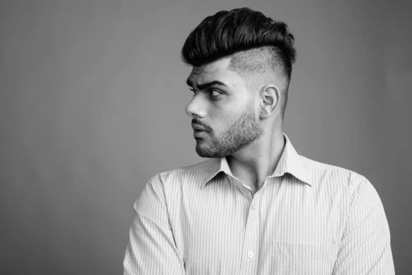 スタジオショットの若いですハンサムなインドのビジネスマンに対して灰色の背景で黒と白 — ストック写真