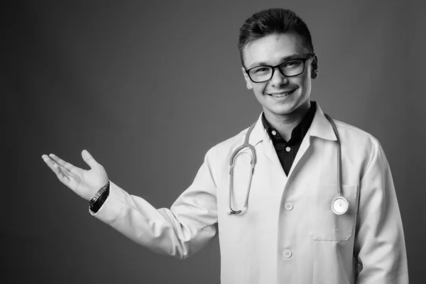 Estudio Joven Guapo Doctor Con Anteojos Sobre Fondo Gris Blanco — Foto de Stock