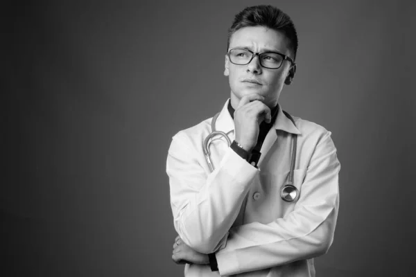 Estudio Joven Guapo Doctor Con Anteojos Sobre Fondo Gris Blanco — Foto de Stock