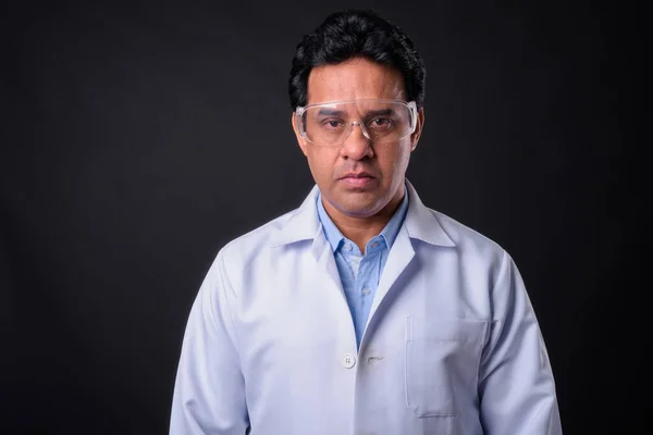 スタジオショットの成熟したインド人男性医師に対する黒の背景 — ストック写真