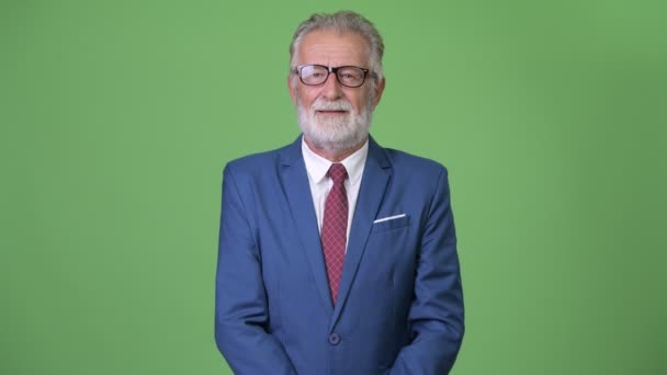 Handsome senior bearded businessman against green background — Stock Video