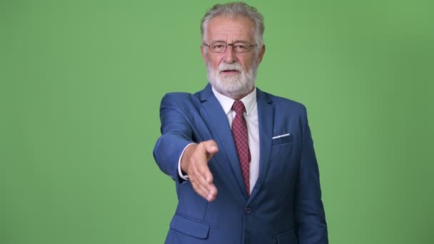 Handsome senior bearded businessman against green background — Stock Video