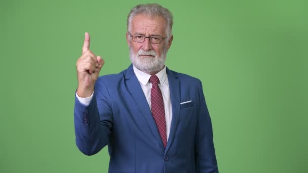 Handsome senior bearded businessman against green background — Stock Video