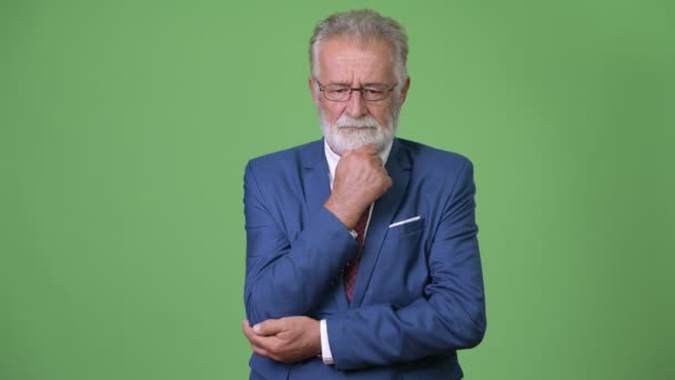 Handsome senior bearded businessman against green background — Stock Video