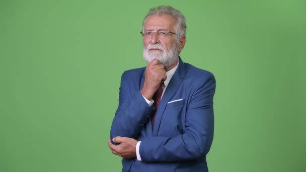 Handsome senior bearded businessman against green background — Stock Video